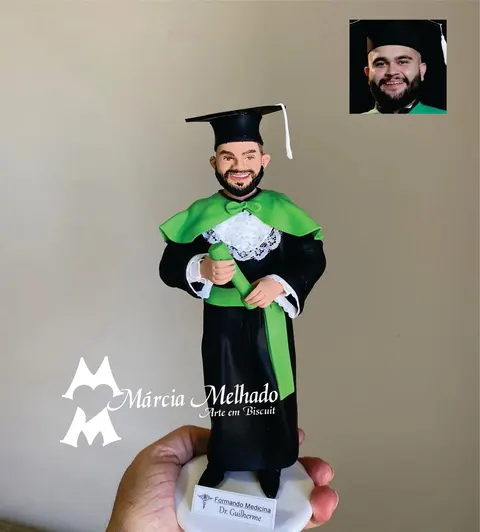 Boneco de biscuit de formando em medicina com beca preta, capa e faixa verdes, capelo e canudo nas mãos
