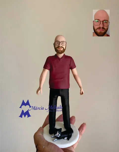 Boneco de biscuit de homem careca de óculos e barba ruiva, camiseta vinho, com gato preto e branco deitado aos pés