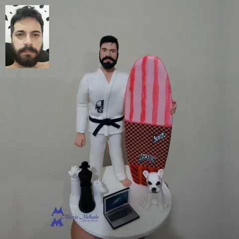 Boneco de barba com kimono branco e faixa preta ao lado de prancha de surf, peças de xadrez, notebook e bulldog francês
