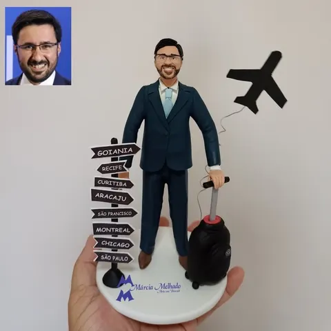 Boneco de biscuit de terno azul com mala de viagem preta, poste de placas com nomes de cidades e silhueta de avião
