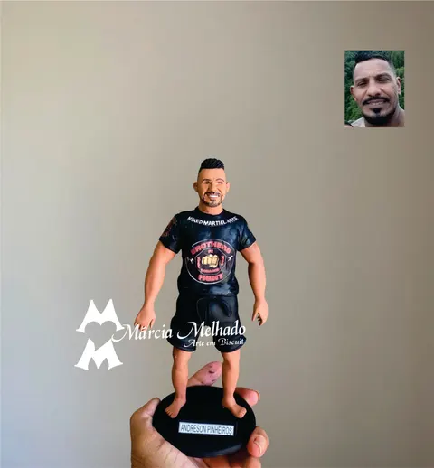 Boneco de biscuit de lutador com camiseta preta de MMA, bermuda preta e pés descalços sobre base preta com plaquinha