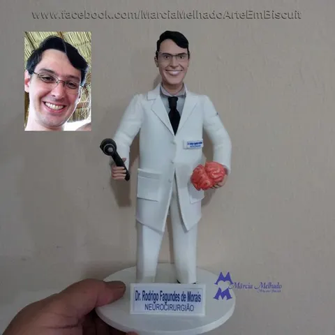 Boneco de biscuit de médico neurocirurgião com jaleco branco e óculos segurando martelo de reflexos e um cérebro