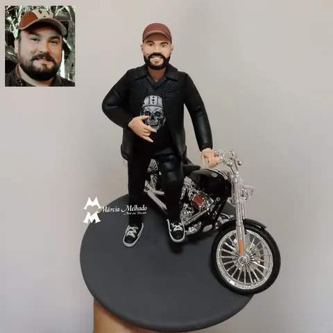 Boneco de biscuit de motociclista barbudo com jaqueta de couro, camiseta de caveira e boné, ao lado de moto chopper