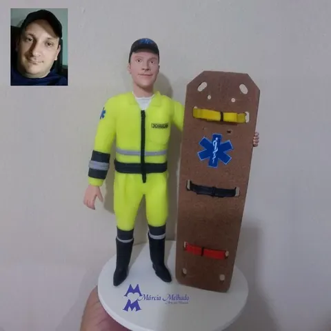 Boneco de biscuit de socorrista com macacão amarelo fluorescente e boné preto segurando uma prancha de resgate