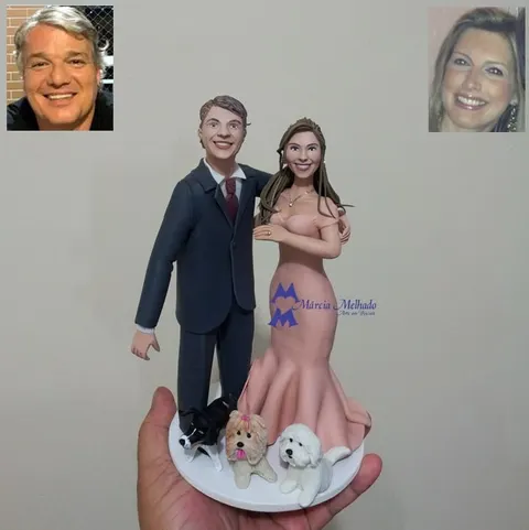 Casal de biscuit: homem de terno cinza com gravata vinho e mulher de vestido longo rosé, com três cachorros na base branca