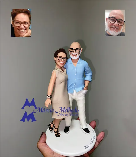 Bonecos de biscuit de casal abraçado, ela de vestido bege e óculos, ele careca de barba branca e camisa azul