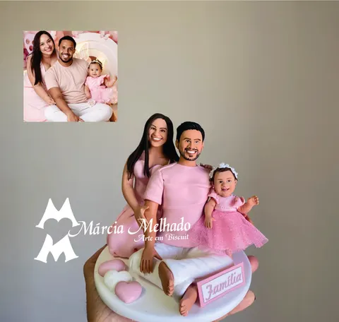 Bonecos de biscuit de família com mãe e pai de roupa rosa sentados e bebê de vestido de tule, plaquinha Família e corações