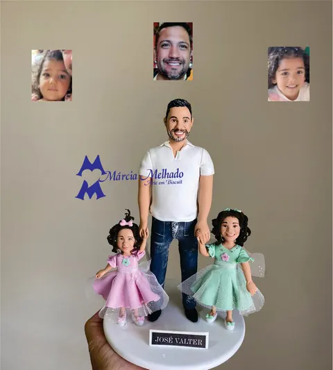 Boneco de biscuit de pai de polo branca e jeans segurando as mãos de duas meninas com vestidos de tule rosa e verde