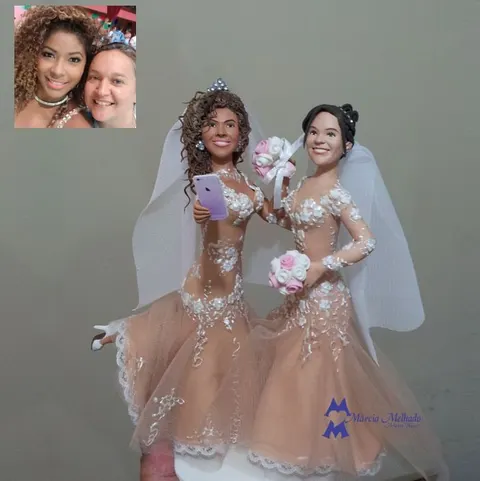 Topo de bolo de biscuit com duas noivas de vestidos nude rendados e véu, uma segurando celular roxo para selfie