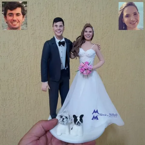 Noivo de terno azul-marinho e gravata borboleta abraçando a noiva de vestido branco, com dois cachorros na base