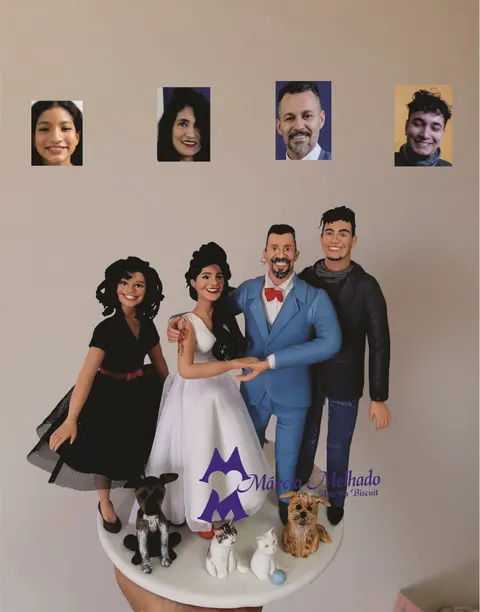 Noivinhos de biscuit com terno azul-claro e vestido branco ao lado da filha, do filho, dois cachorros e dois gatos