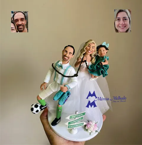 Noivinhos de biscuit: noivo de terno branco com bola de futebol e tênis de corrida, noiva com filha no colo e placa de setas