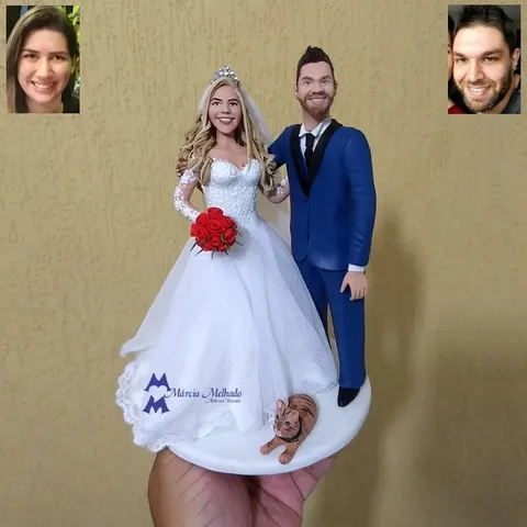 Topo de bolo de biscuit com noiva loira de vestido rendado, noivo de terno azul e gato rajado laranja na base