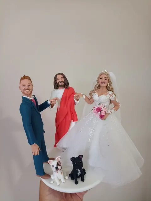 Noivinhos de biscuit com Jesus unindo as mãos do casal, noivo de terno azul, noiva de vestido rendado e dois buldogues