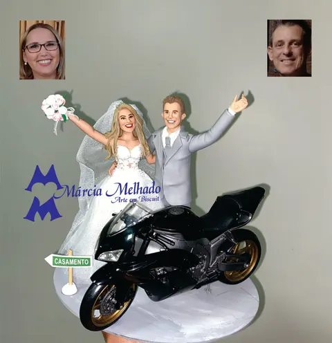 Noivinhos de biscuit de braços erguidos atrás de moto esportiva preta de rodas douradas, com placa de estrada casamento