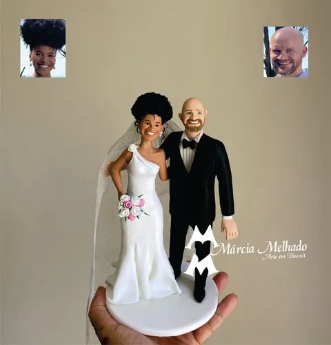 Noivinhos de biscuit: noiva de vestido branco de um ombro só com véu e buquê ao lado do noivo careca de barba e smoking preto