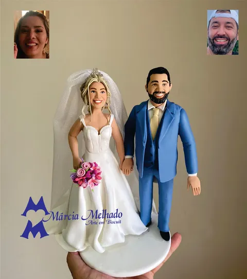 Noivinhos de biscuit de mãos dadas, noiva loira de véu e buquê de flores rosa e noivo de barba com terno azul e gravata bege