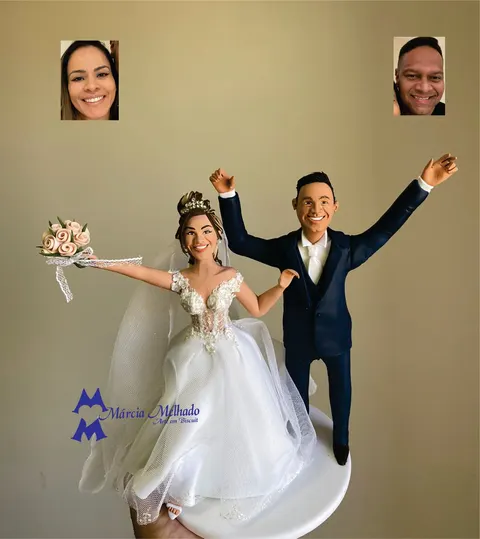 Noivinhos de biscuit comemorando de braços erguidos, noiva de vestido rendado com buquê de rosas e noivo de terno azul