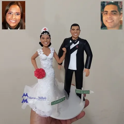 Topo de bolo de biscuit com noiva enfermeira de touca com cruz vermelha e noivo de terno com camisa do Vasco e placas de rua